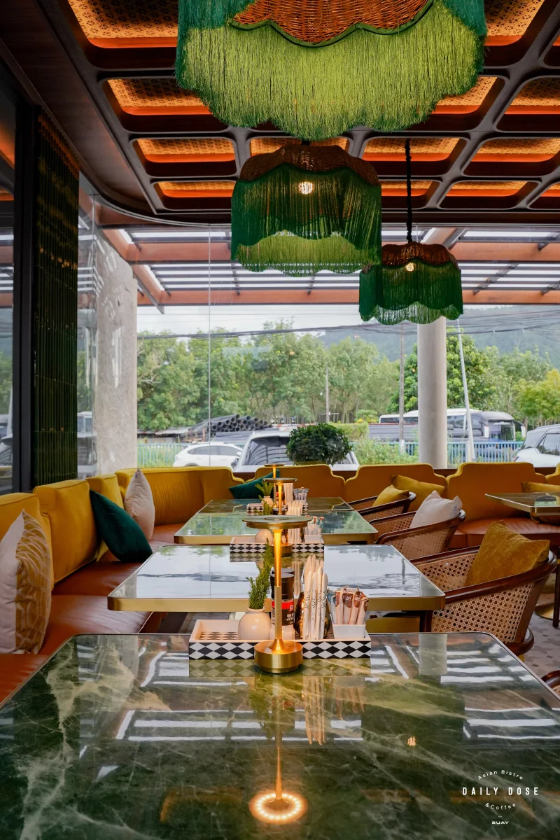 Yellow velvet booths and marble tables under green fringed lamps