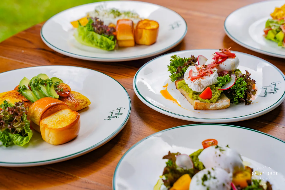 Breakfast plates of eggs Benedict, brioche toast and salad on a wooden table
