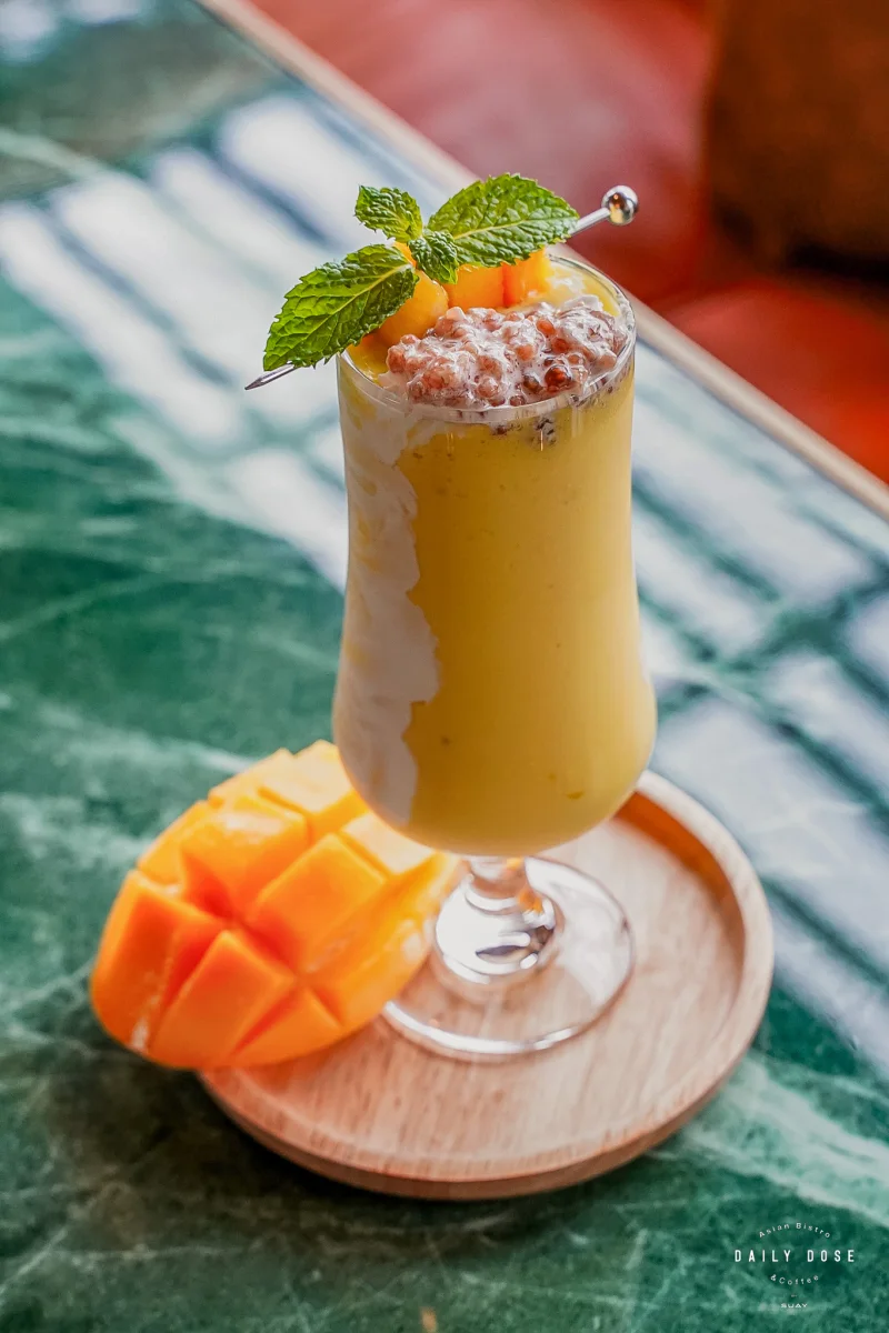 Mango smoothie topped with mint, with fresh mango on the side