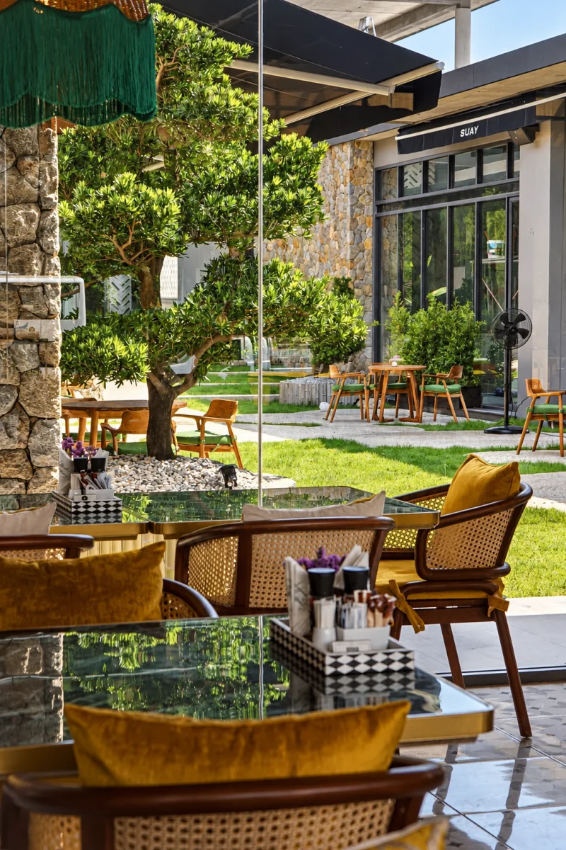 Terrace seating under a sculpted tree beside the garden lawn